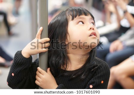 Asian children cute or kid girl enjoy and fun in bogey of sky train or electric train and holding rail for travel or transport in city on holiday