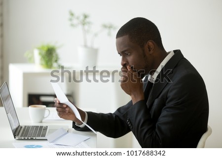 Shocked african-american businessman frustrated by notification about loan debt, confused stunned black employee feeling stressed reading unexpected bad news in letter, got dismissed fired in notice Royalty-Free Stock Photo #1017688342