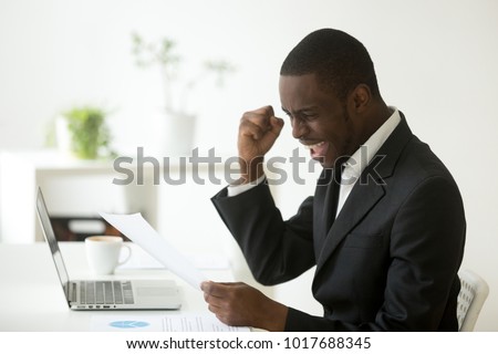 Excited african-american businessman holding letter with unexpected good news, happy black entrepreneur celebrating unbelievable win success achievement reading notification notice, got job promotion Royalty-Free Stock Photo #1017688345