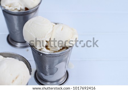Frosty metal cups filled with scoops of creamy vanilla ice cream.