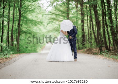 Young happy couple kissing, wedding day, two newlyweds on road