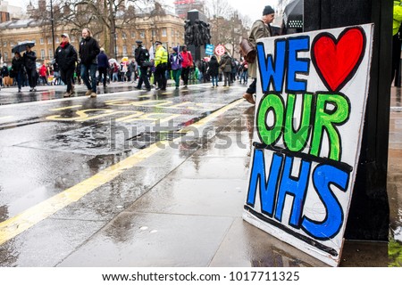 London, England. 3rd February 2018. EDITORIAL. WE LOVE OUR NHS poster sits in the rain at the NHS In Crisis demonstration through central London, in protest of underfunding & privatisation of the NHS. Royalty-Free Stock Photo #1017711325