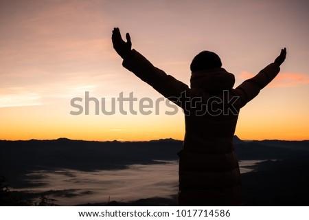 Silhouette of a man with hands raised in the sunset. Religion concept.