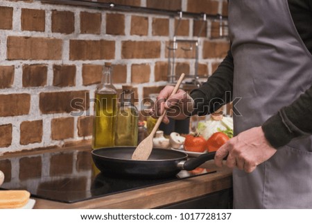 cropped image of man stirring vegetables on frying pan