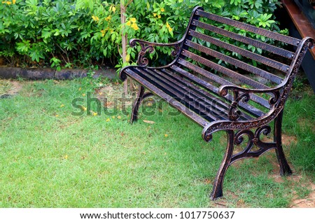 Vintage style wrought iron bench with water droplet in green garden after the rain
