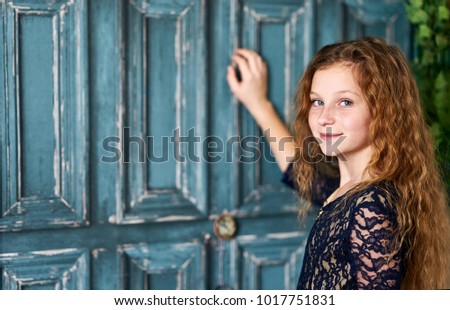 Red-haired little girl in front of blue door