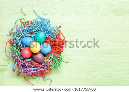 Photo of multi-colored Easter eggs on green wooden background with blank space