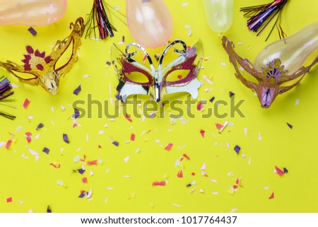 Table top view aerial image of beautiful colorful carnival mask background.Flat lay accessory object on modern yellow paper at home office desk studio.Creative design text for the festival backdrop.