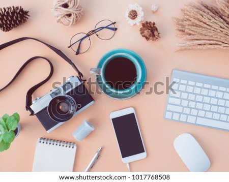 top view coffee shop and office table concept with coffee cup, retro camera, notebook, glasses, keyboard, smartphone on Pastel Color table background.