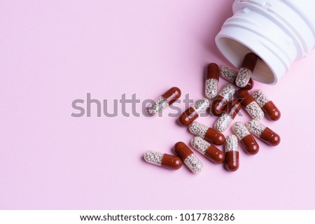 Transparent pills and pill bottle on blue background Royalty-Free Stock Photo #1017783286