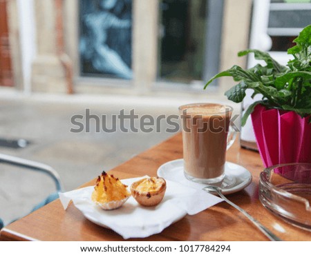 Coffee with milk and pastel de nata and  in outdoor portuguese cafe
