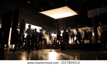 Behind the scenes of video shooting production crew team silhouette and camera equipment in studio. 