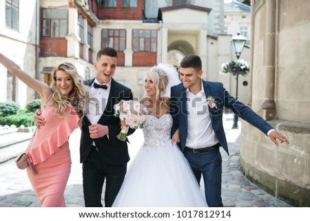 The bride,bridesmaid,groomsman and groom walking along street Royalty-Free Stock Photo #1017812914