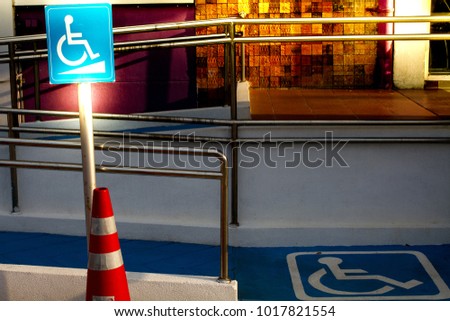 Wheelchair Accessible Symbol White on blue Sign /(International) Wheelchair /Blue Handicap Symbol/ in front of the  office and   blue footpath  with beautufiul color in sunset