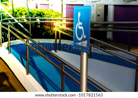 Wheelchair Accessible Symbol White on blue Sign /(International) Wheelchair /Blue Handicap Symbol/ in front of the  office and   blue footpath  with beautufiul color in sunset