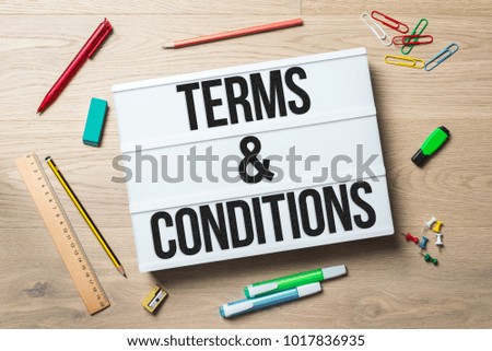 Terms and conditions writing in lightbox with pen, pencil, highlighter and ruler lying on office desk as flat lay