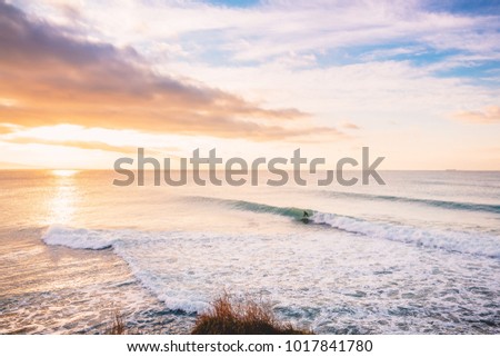 Surfer ride on perfect barrel wave. Landscape with waves and sunrise colors