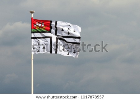The flag of the city of Nantes, France, waving in the wind, against a ominous cloudscape