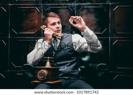 the younge man holding the bitcoin in the hand and talking by phone in a vintage room