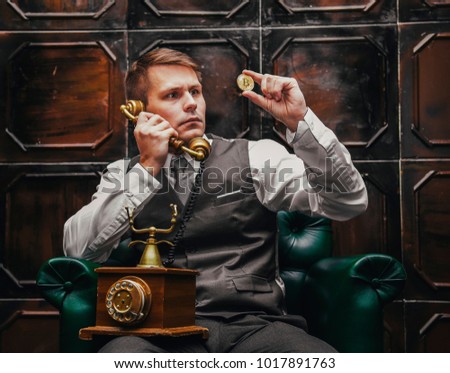 the younge man holding the bitcoin in the hand and talking by phone in a vintage room
