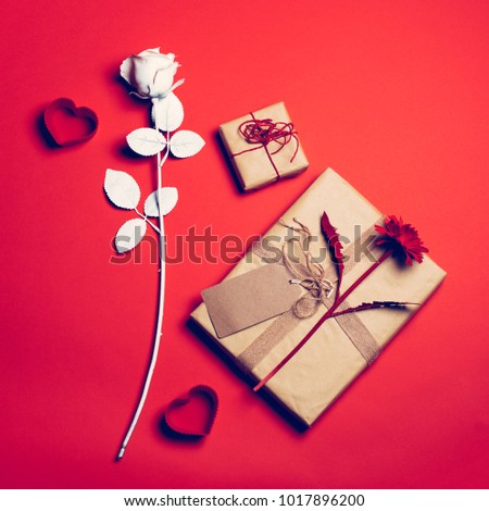 Valentine composition on the red background with flowers, hearts and cartoon packages. Valentine's day. Love concept.