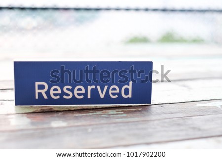 The sign ‘Reserved’ tag on the wooden table for the privilege private area for customer at the restaurant with blurred background with copy space