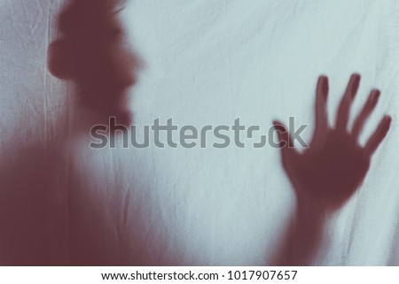 scary blurry silhouette of unrecognizable person screaming behind veil