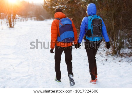 Picture from back of man and woman with backpacks in winter forest