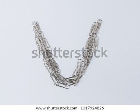 Letter V displayed with paperclips on white background