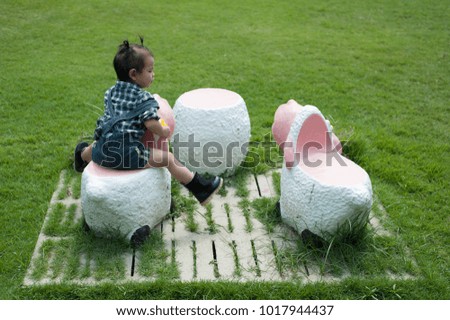 Asian Cute girl baby happy in the garden lonely,Cute baby happy with playing on  cartoon statue