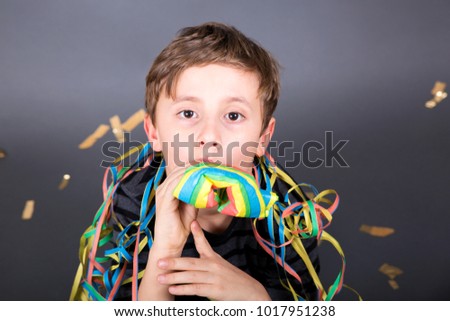 young boy with a carnival flute sitting on the floor. confetti golden