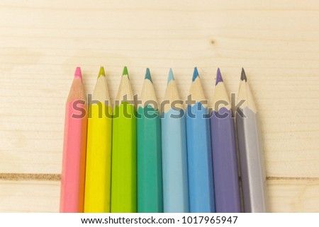 Colored pencils laid along the colors of the rainbow on a light wooden background