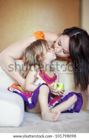 Mother with her small daughter playing on the sofa at home