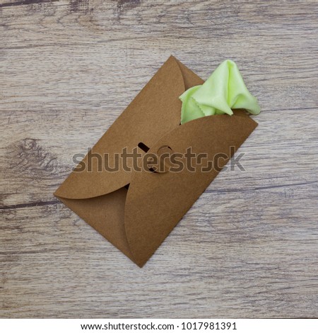 A bright green napkin sticks out of the craft envelope. top view