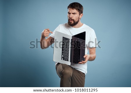 emotion, a man with a beard holds a laptop on his knee on a blue background                               
