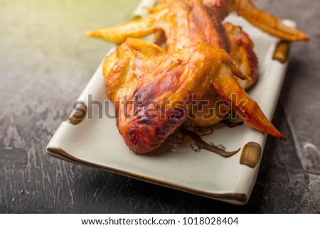 A plate of chicken wings on a dark background. Crispy grilled chicken 