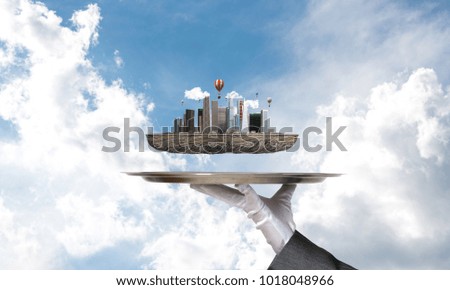 Cropped image of waitress's hand in white glove presenting modern city block on metal tray with blue cloudy skyscape on background. 3D rendering.