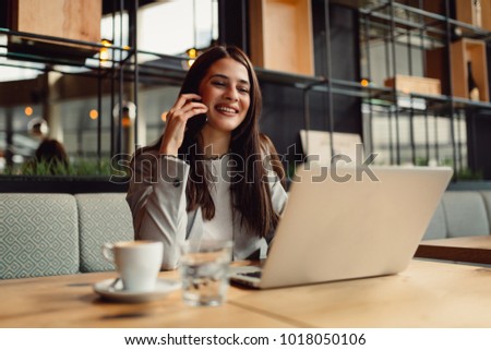 Business woman talking on mobile and working online.