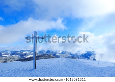 Belchen in winter. Mountain top cross - high dynamic range image of a crucifix. Winter wonderland at Belchen in the Black Forest. Summits and fires covered with snow. Blue sky with Clouds. 