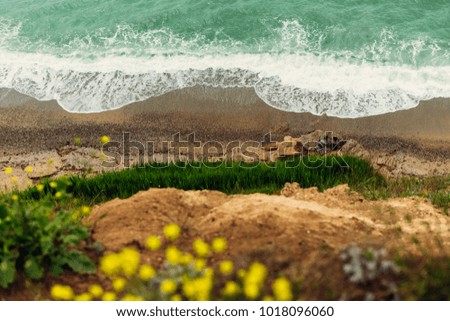 top view of the turquoise sea and white foam, sandy beach