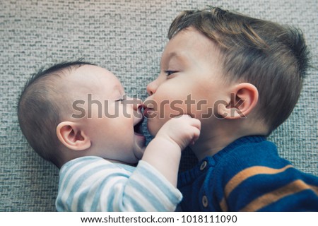 Toddler baby boy kisses his happy brother Royalty-Free Stock Photo #1018111090