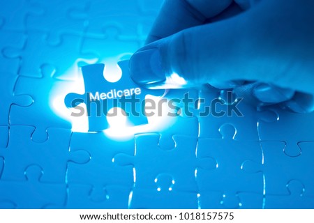 Health Care Concept. Doctor holding a jigsaw puzzle with medicare word. Royalty-Free Stock Photo #1018157575