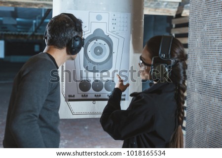 shooting instructor pointing on used target in shooting range Royalty-Free Stock Photo #1018165534