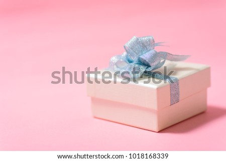 Silver gift box with blue ribbon on pink background, present for giving in special day and holiday
