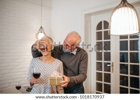 Elderly man surprising his wife with a gift