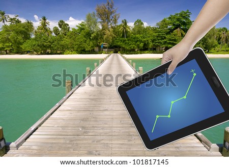 Hand holding digital tablet PC with a path to paradise island background