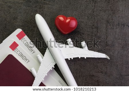 Travel lover, honeymoon trip or valentine's gift concept, toy airplane, boarding pass and passport with red and pink heart shape on black texture chalkboard with copy space.