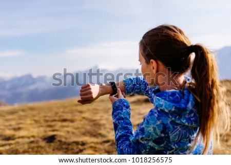 woman tourist looking at fitness bracelet on the background of mountains Royalty-Free Stock Photo #1018256575