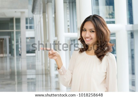 business woman pointing sideway to blank space, office building rental space offer concept