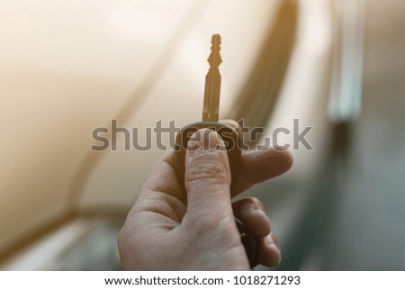 Man holding car keys with car on background.